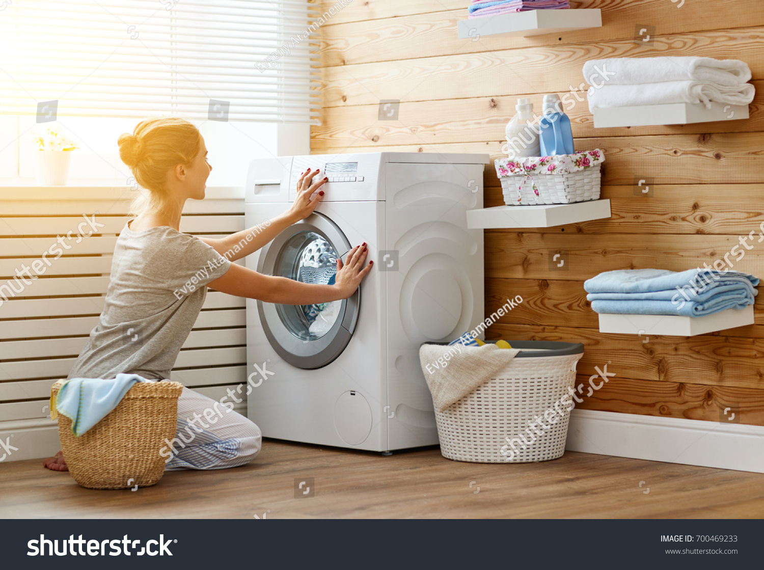 a Happy housewife woman in laundry room with washing machine  
