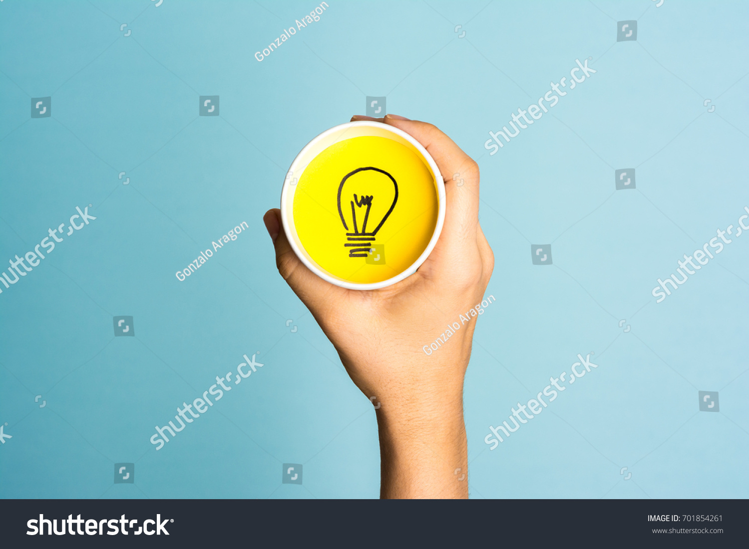 New idea concept. Hand holding a paper cup with lightbulb symbol.