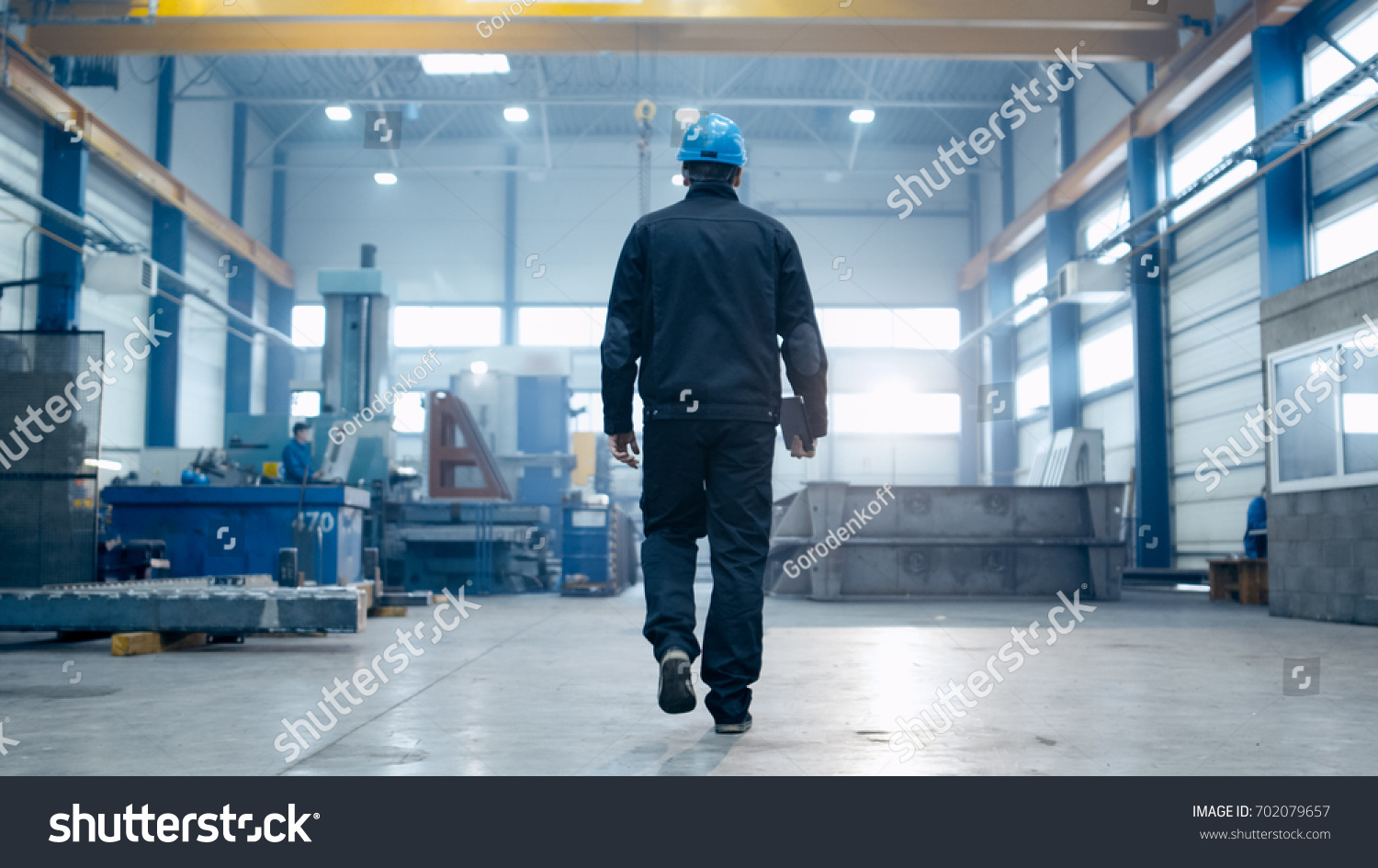 Factory worker in a hard hat is walking through industrial facilities.