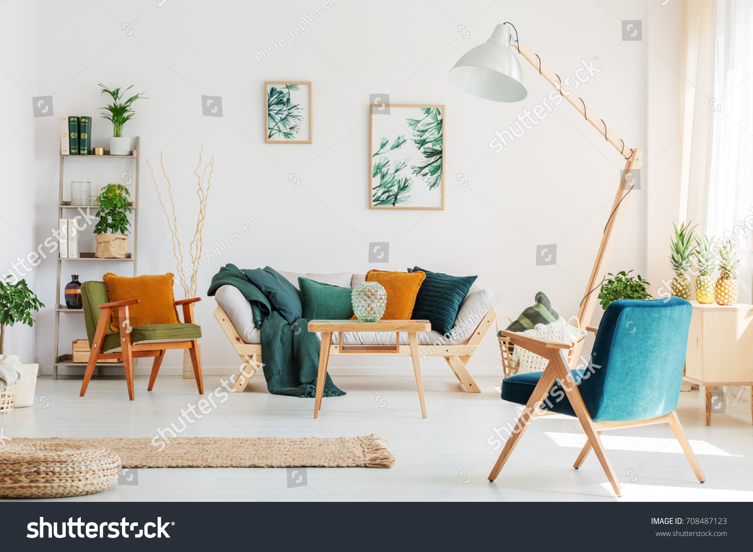 Blue chair and design lamp in natural living room with plants and two paintings on white wall