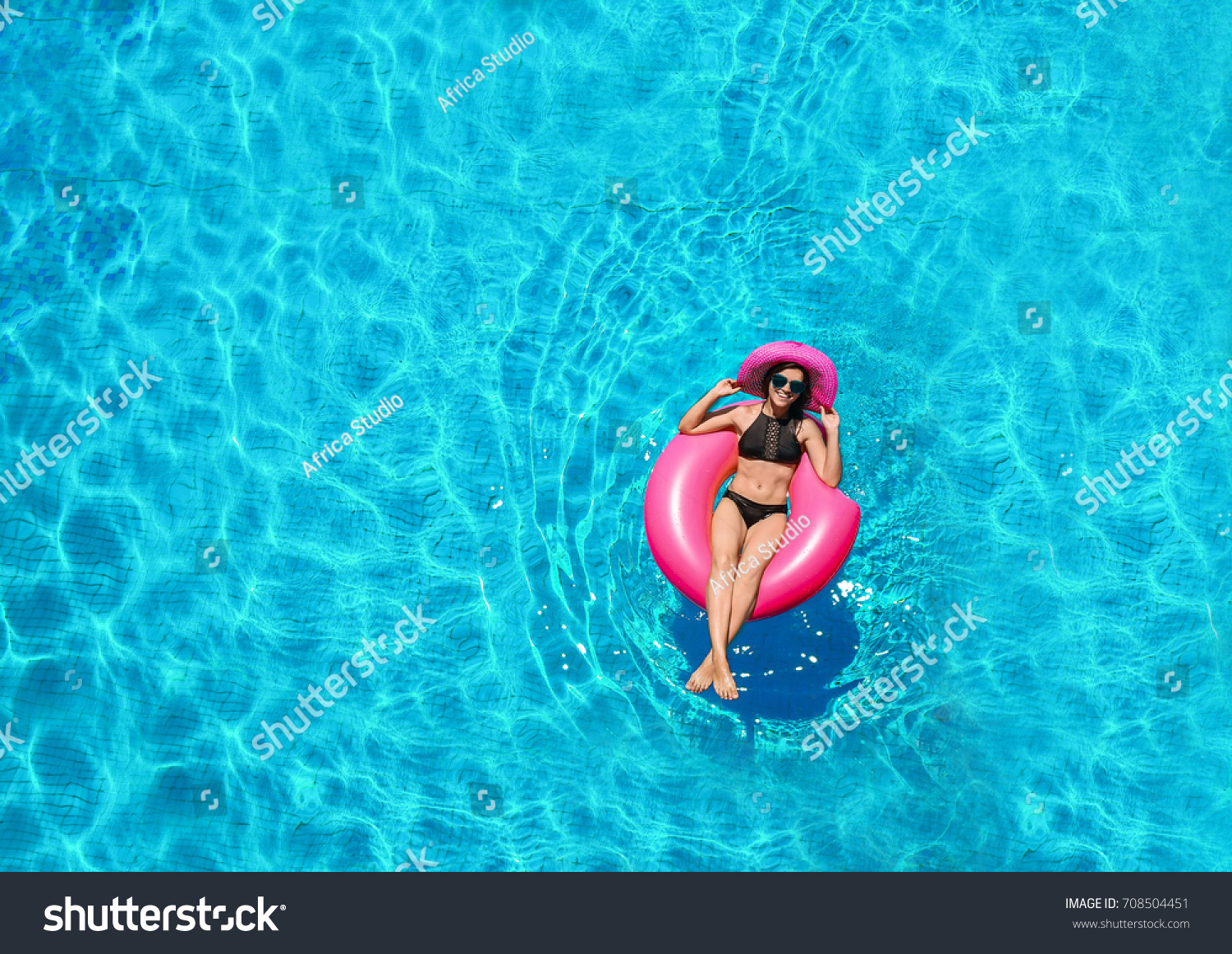 Beautiful young woman with inflatable donut in swimming pool
