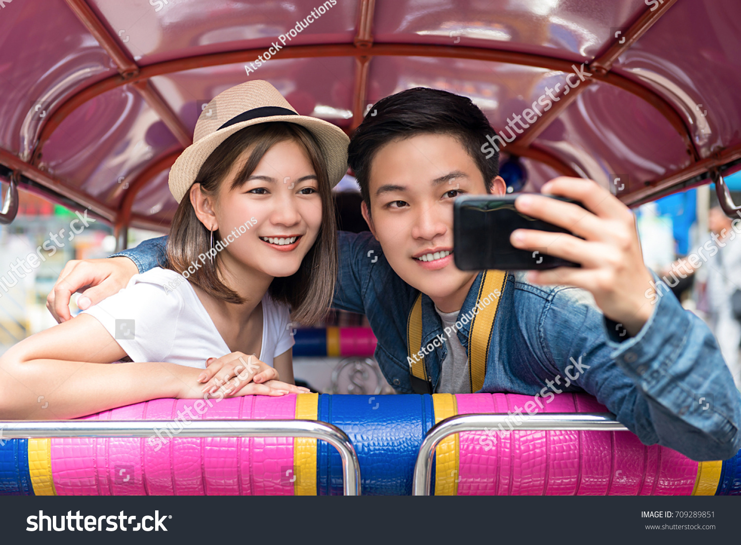 Young Asian couple tourists taking selfie while traveling on local colorful Tuk Tuk taxi exploring Bangkok city  Thailand