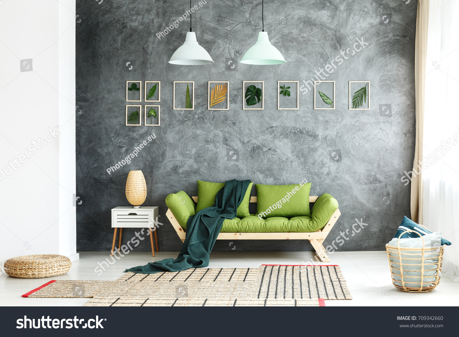 Dark green blanket thrown on wooden couch standing in living room with wicker basket and footrest