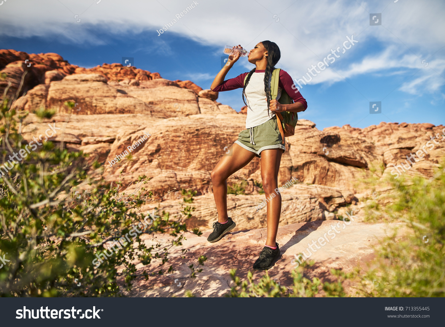 athletic african american female hiker drinking from water bottle at red rock canyon