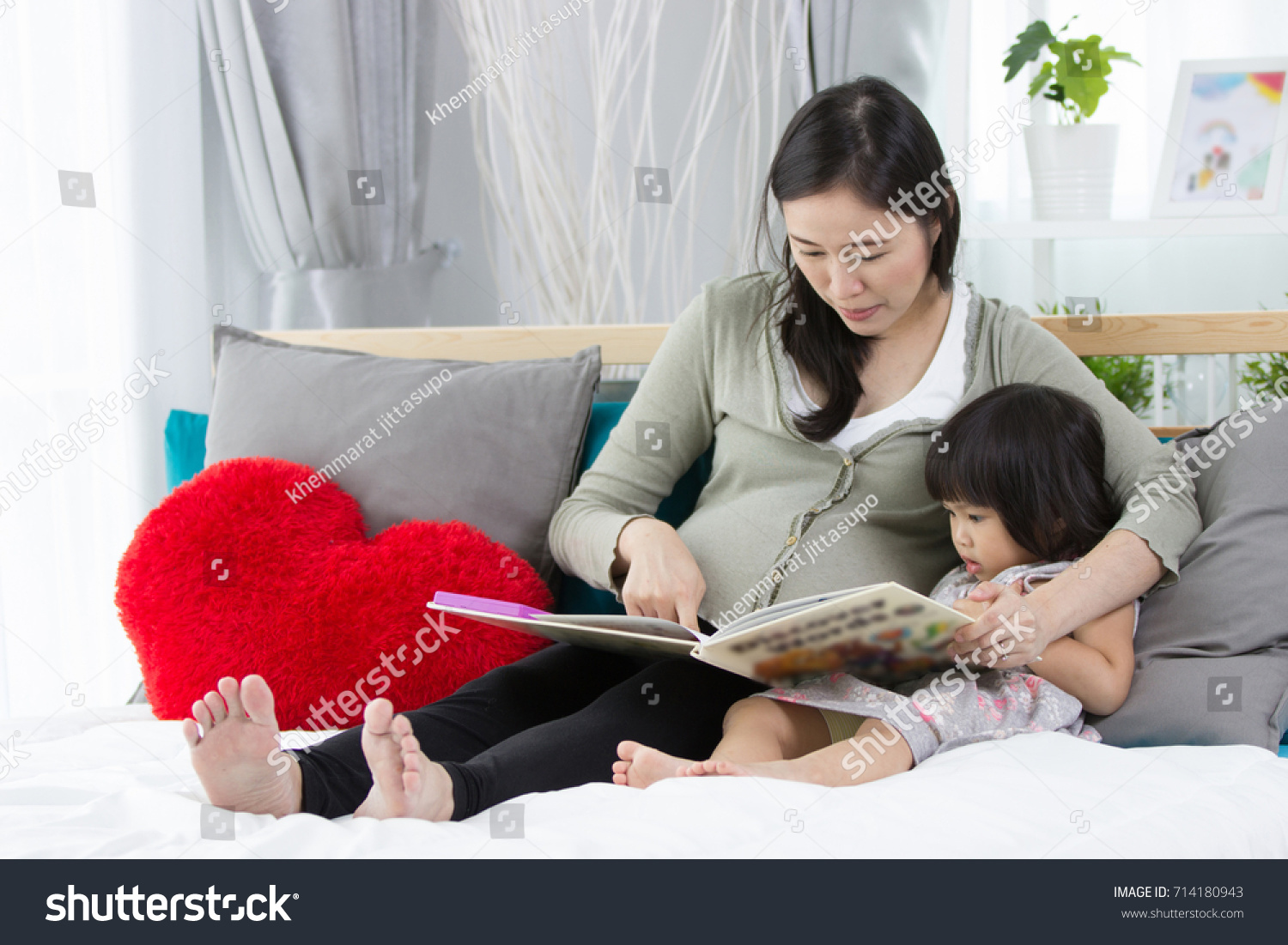 pretty young mother reading a book to her daughter.