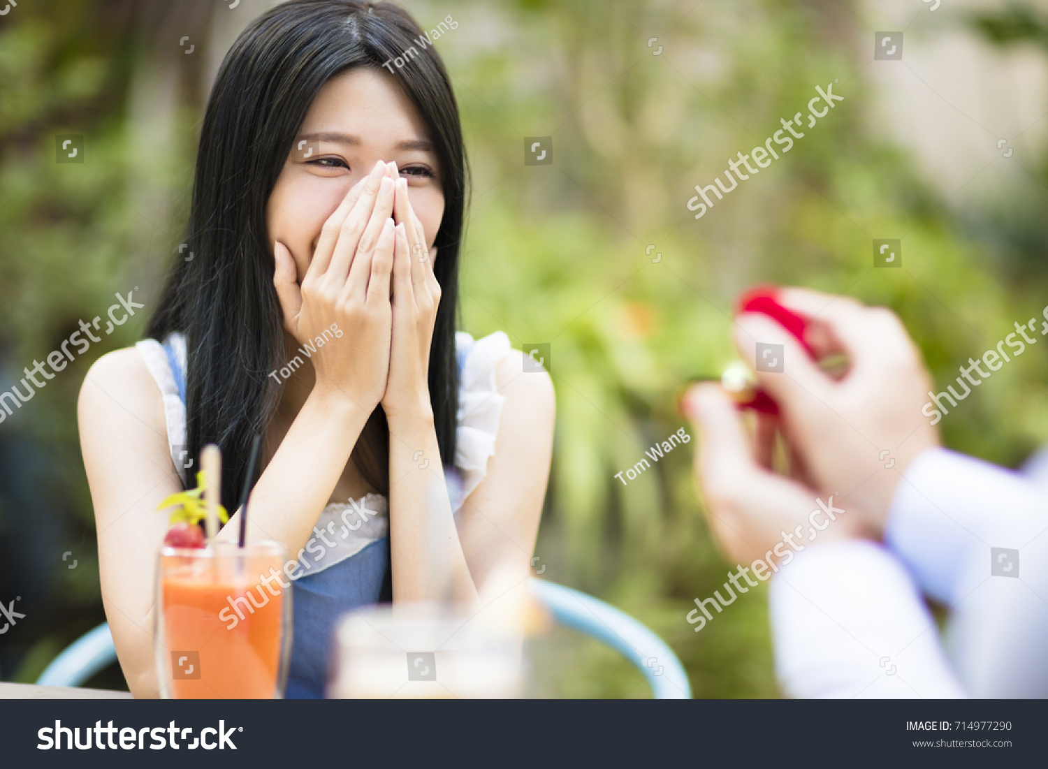 Man showing engagement ring diamond to girlfriend in restaurant
