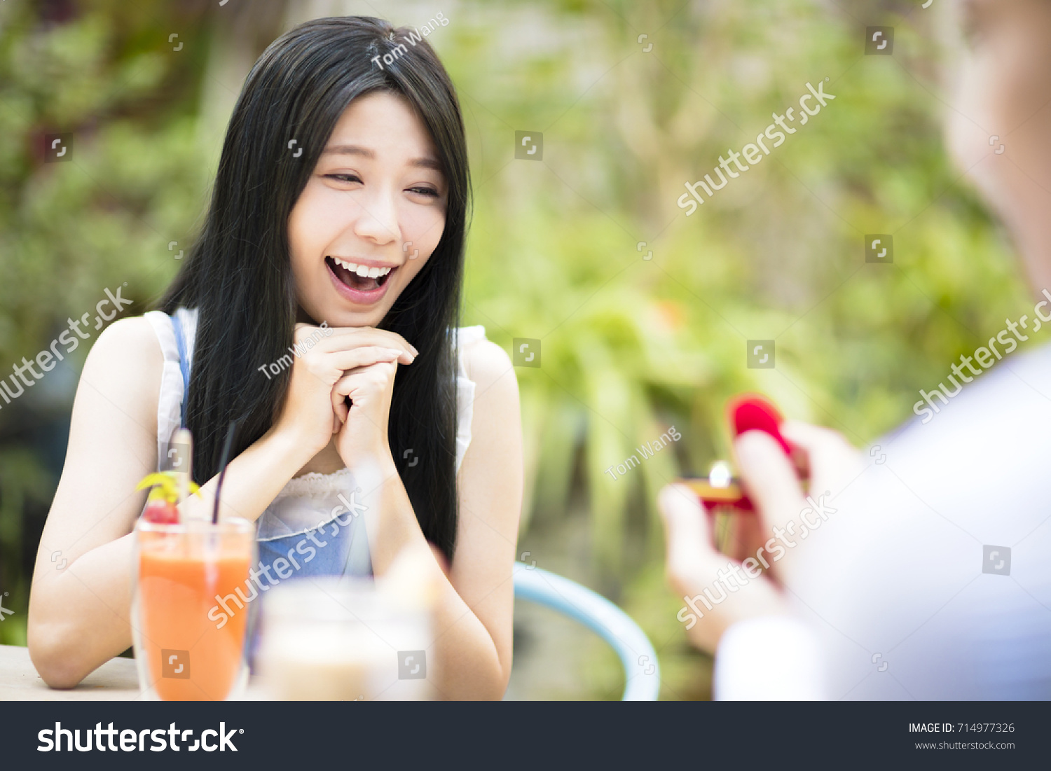 Man showing engagement ring diamond to girlfriend in restaurant