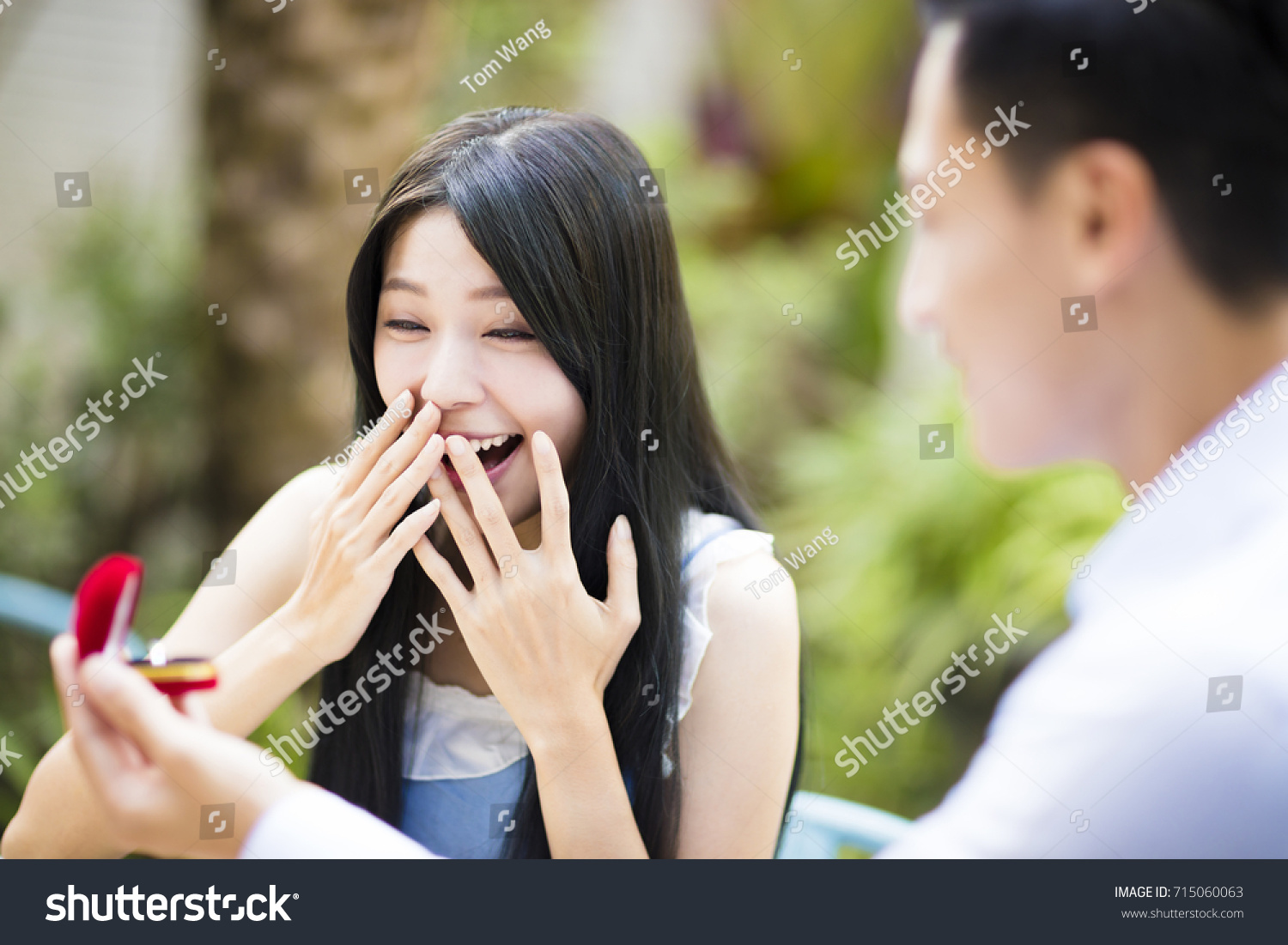Man proposing to girlfriend offering engagement ring in restaurant
