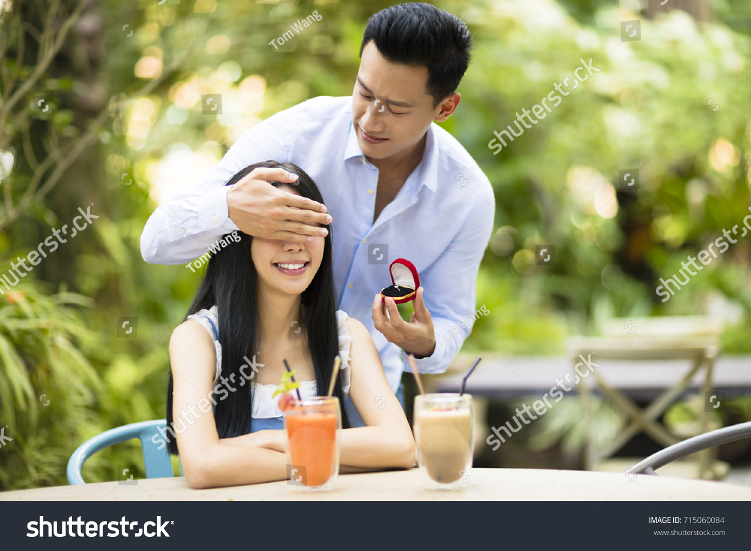 Man proposing to girlfriend offering engagement ring in restaurant