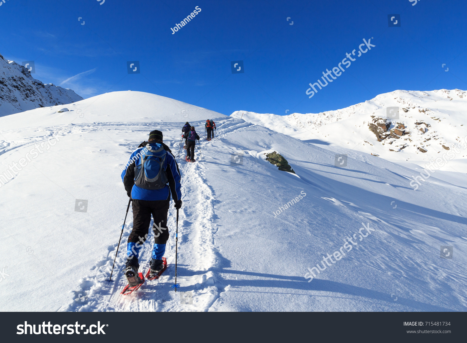 Group of people hiking on snowshoes and mountain snow panorama with blue sky in Stubai Alps  Austria