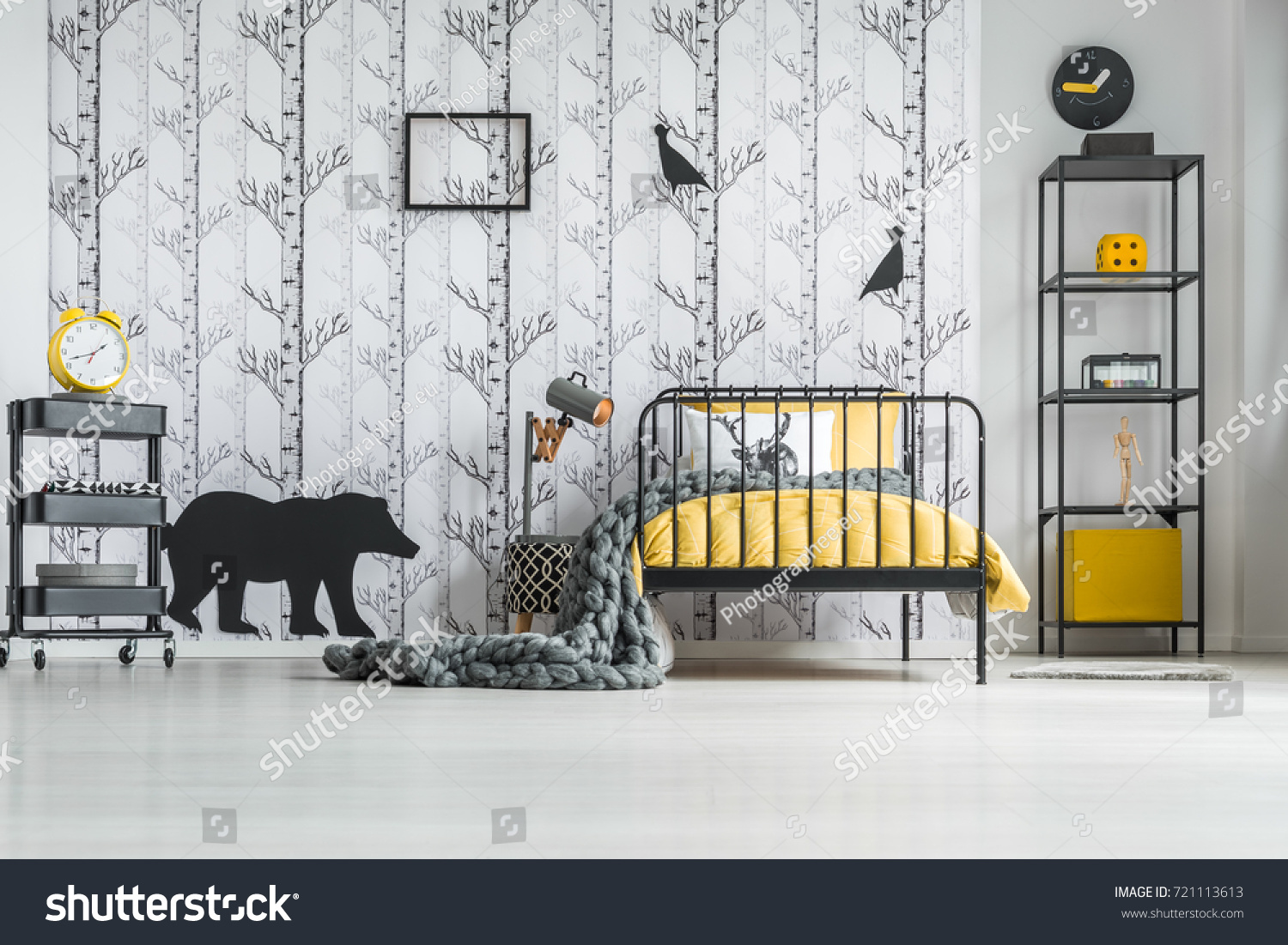 Knit grey blanket on yellow overlay of child's bed in white bedroom