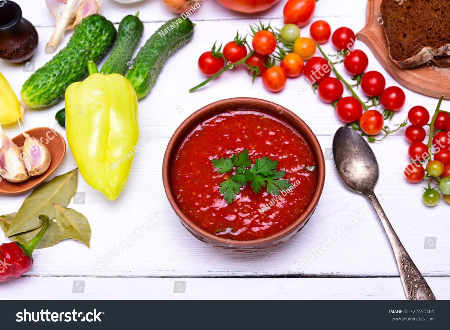 thick soup of tomato and vegetables gazpacho in a brown round plate on a white table