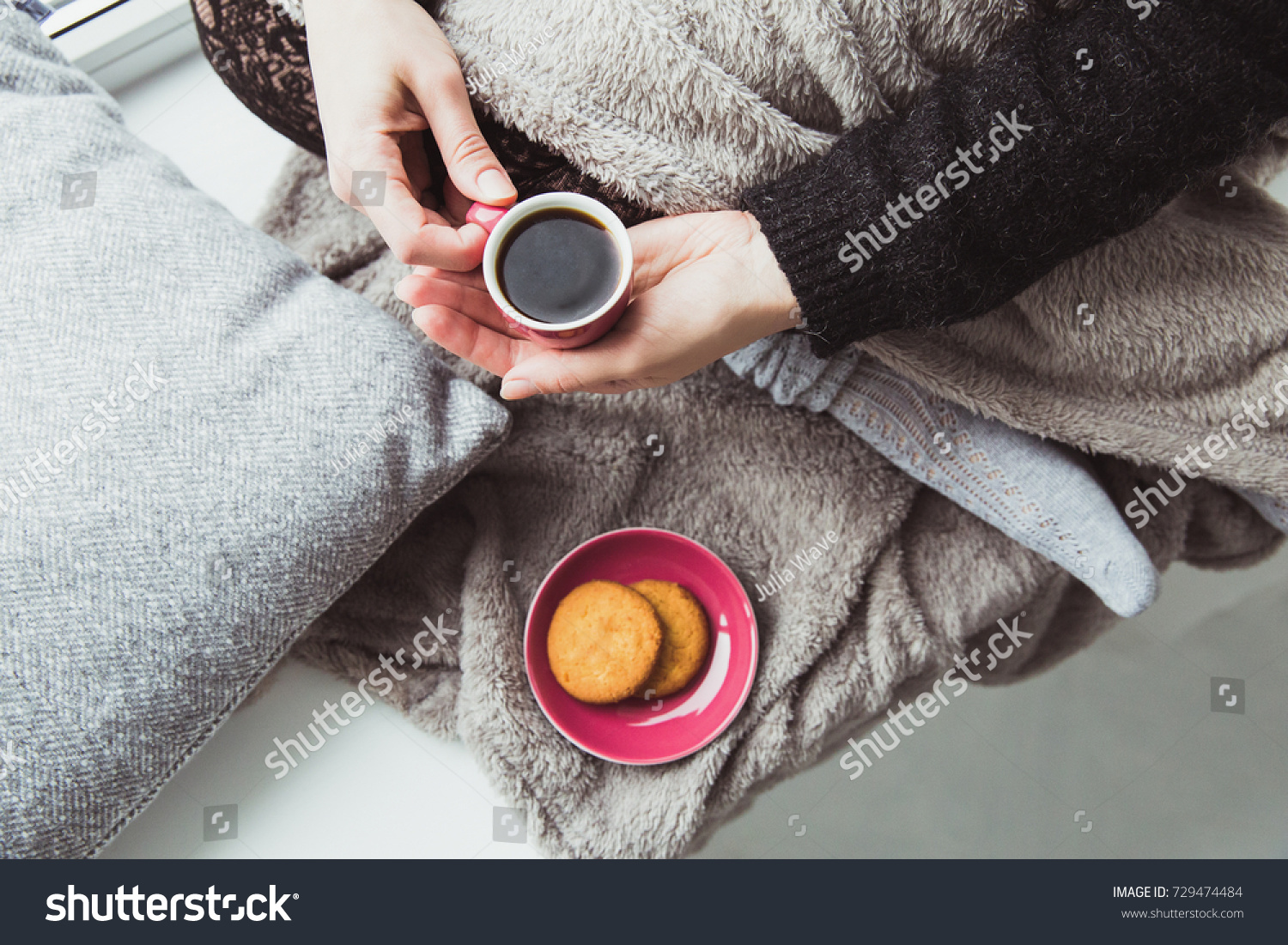 Woman in warm clothes with tiny cup of black bitter coffee in hands. Plate with cookies and girl with coffee cup. Winter cozy atmosphere breakfast concept