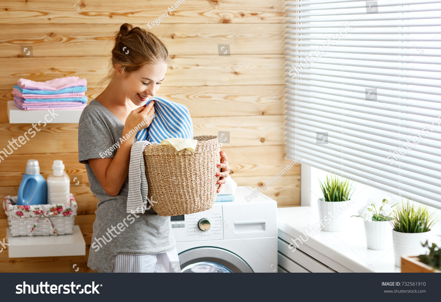 a Happy housewife woman in laundry room with washing machine  

