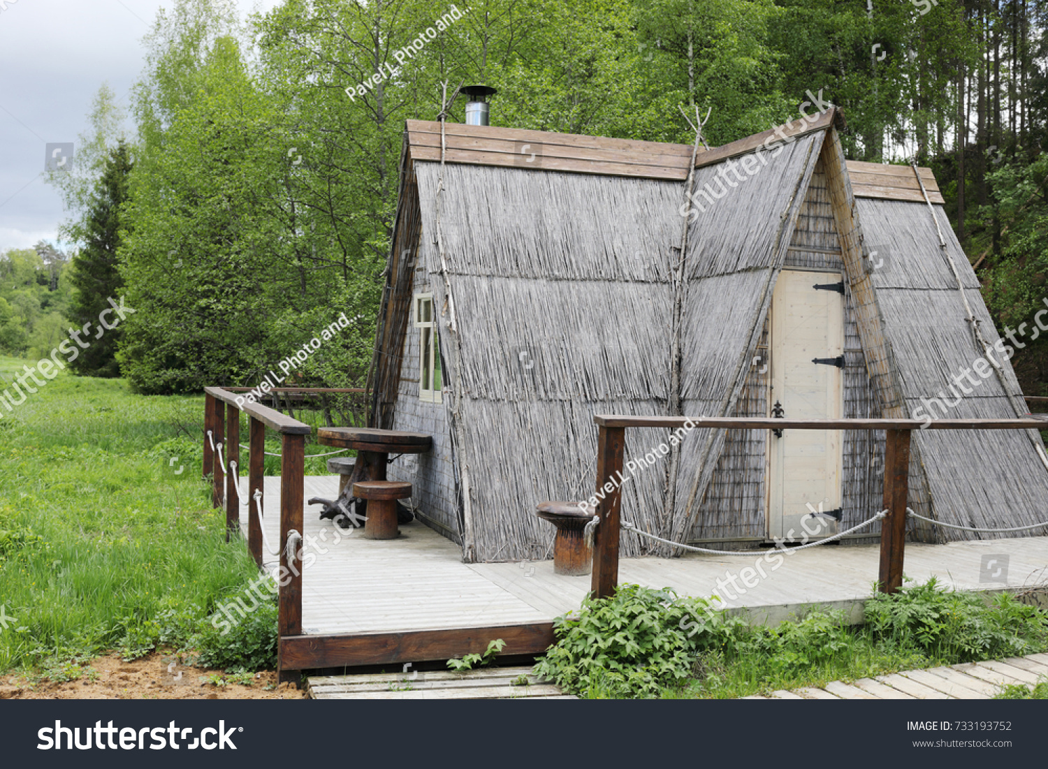 Wooden triangle house in green forest in overcast summer day