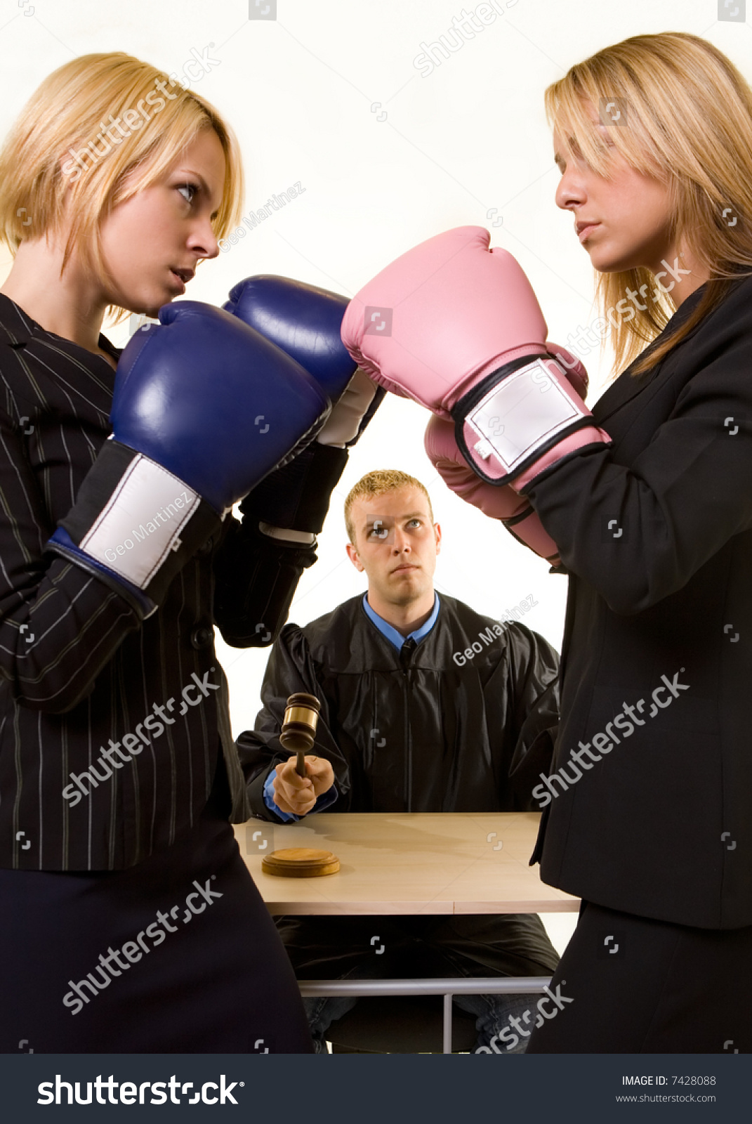 Two women lawyers wearing boxing gloves facing each other with a judge in background judge in focus