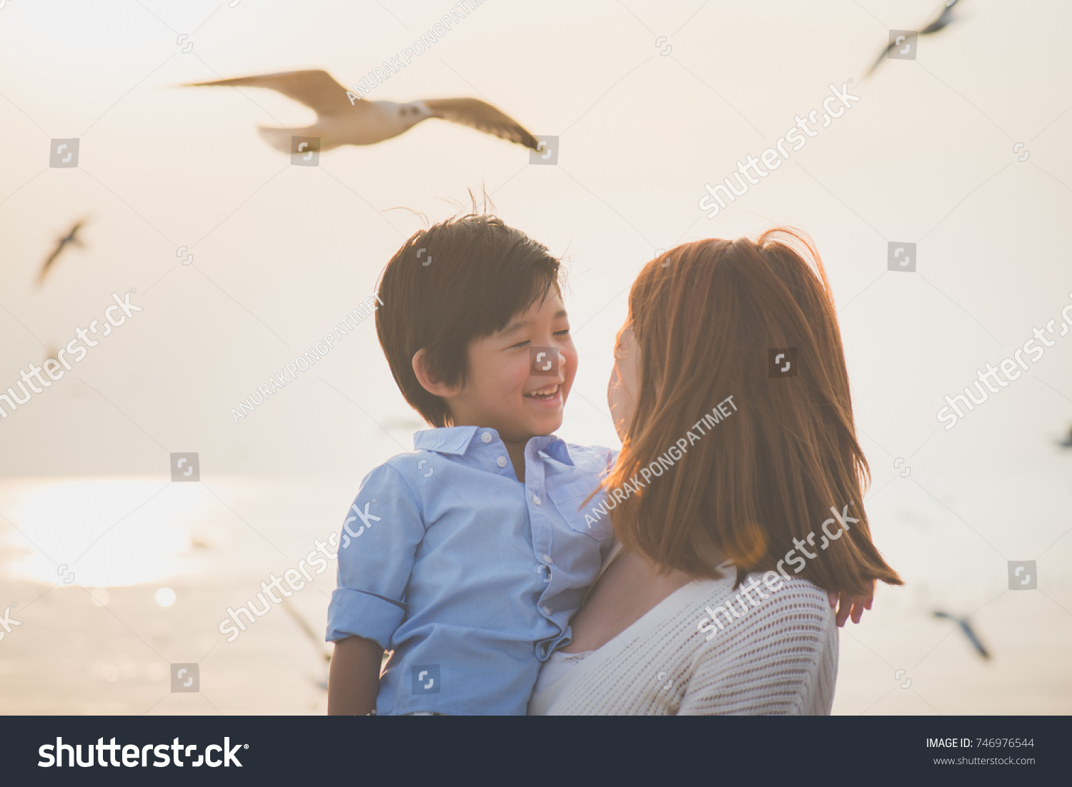 Happy Asian mother and son playing on the beach