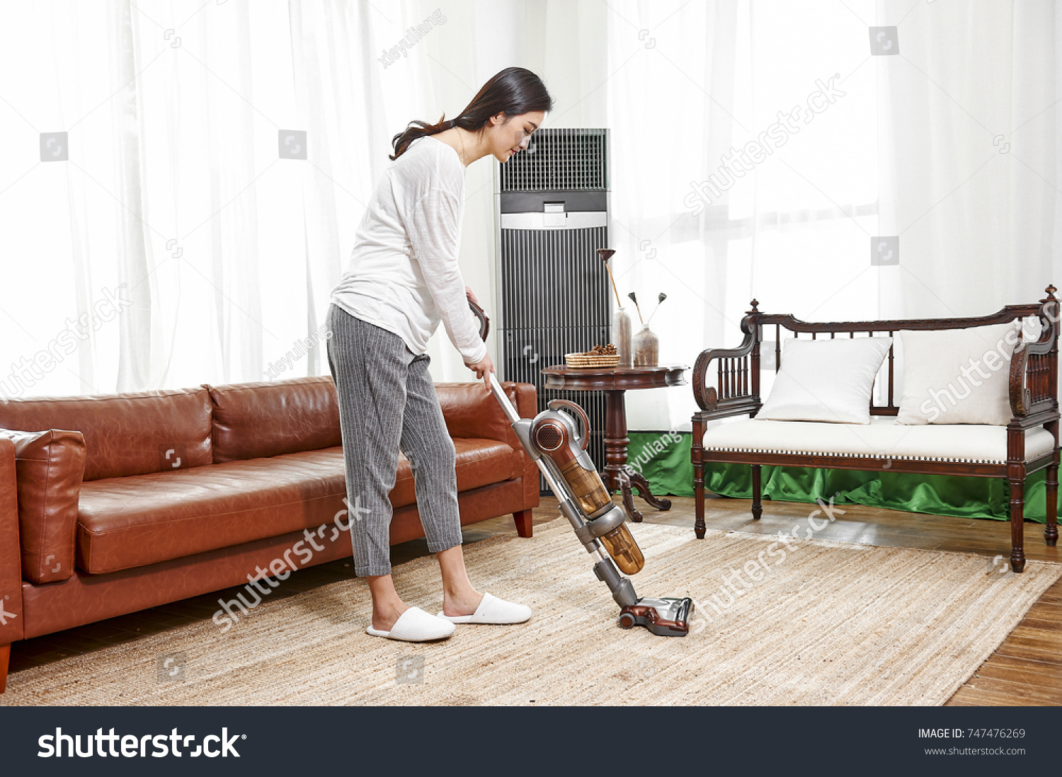 Young asian woman with vacuum cleaner cleaning