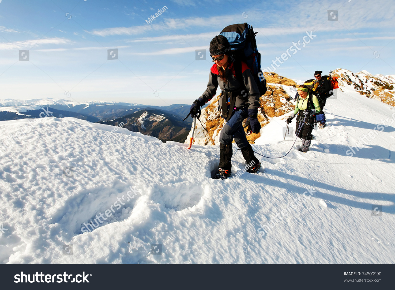 Team of three alpinists climbing a mountain