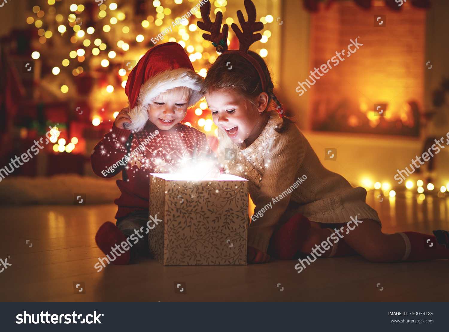 Merry Christmas!happy children with magic gift at home near Christmas tree and fireplace