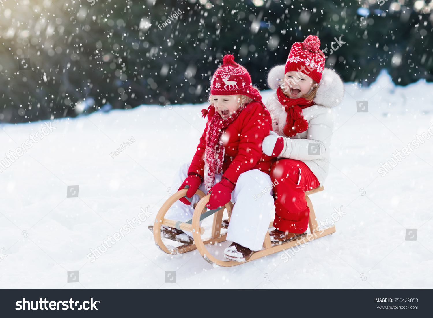 Little girl and boy enjoy a sleigh ride. Child sledding. Toddler kid riding a sledge. Children play outdoors in snow. Kids sled in Alps mountains in winter. Outdoor fun for family Christmas vacation.