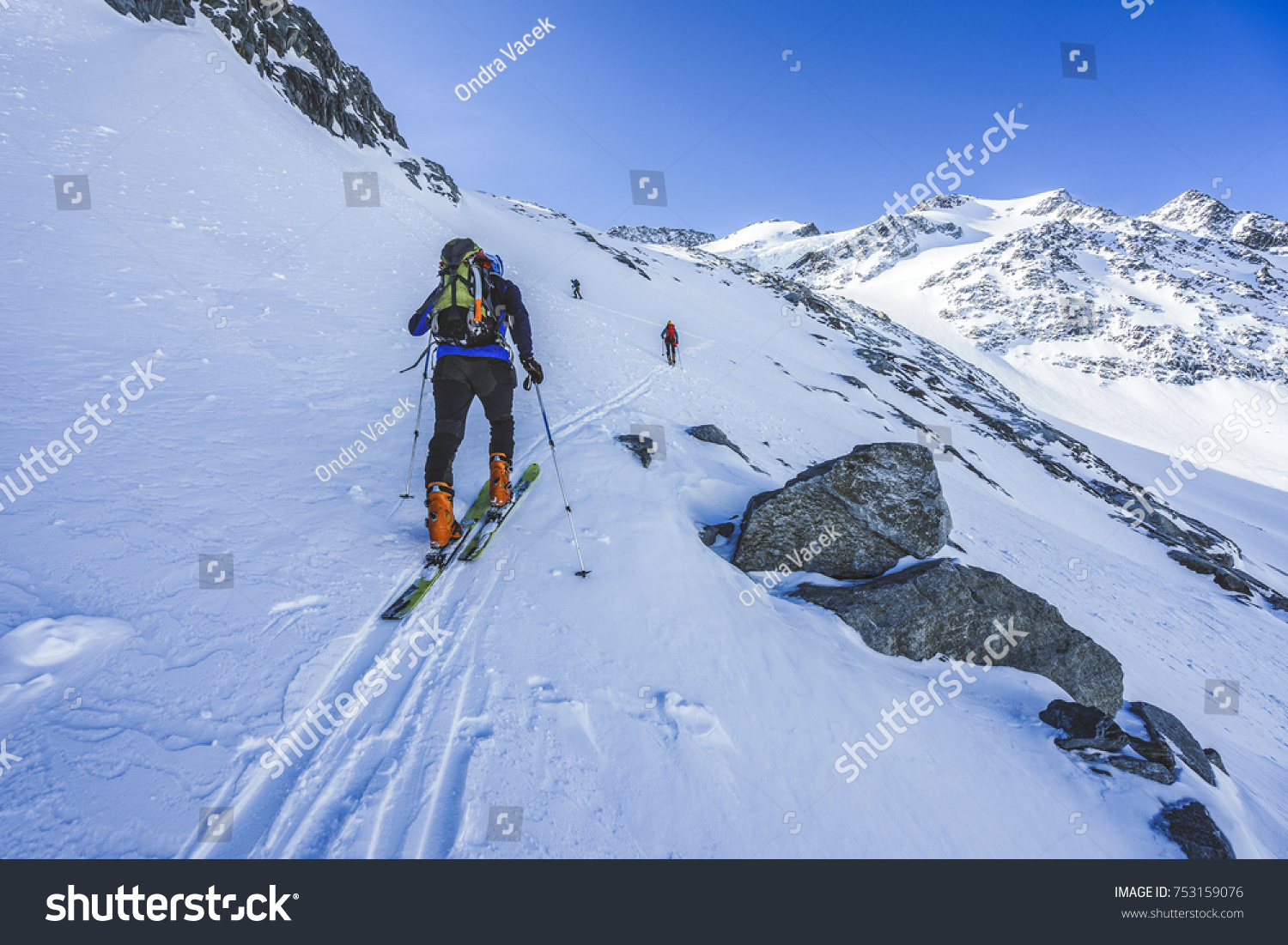 Ski touring in high alpine landscape. Ascent and descent to a summit of an alpine peak. Snow and winter activities skitouring in mountains.