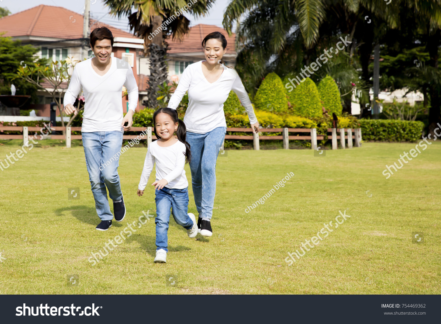 happy asian family running in the park. daughter mother and father.