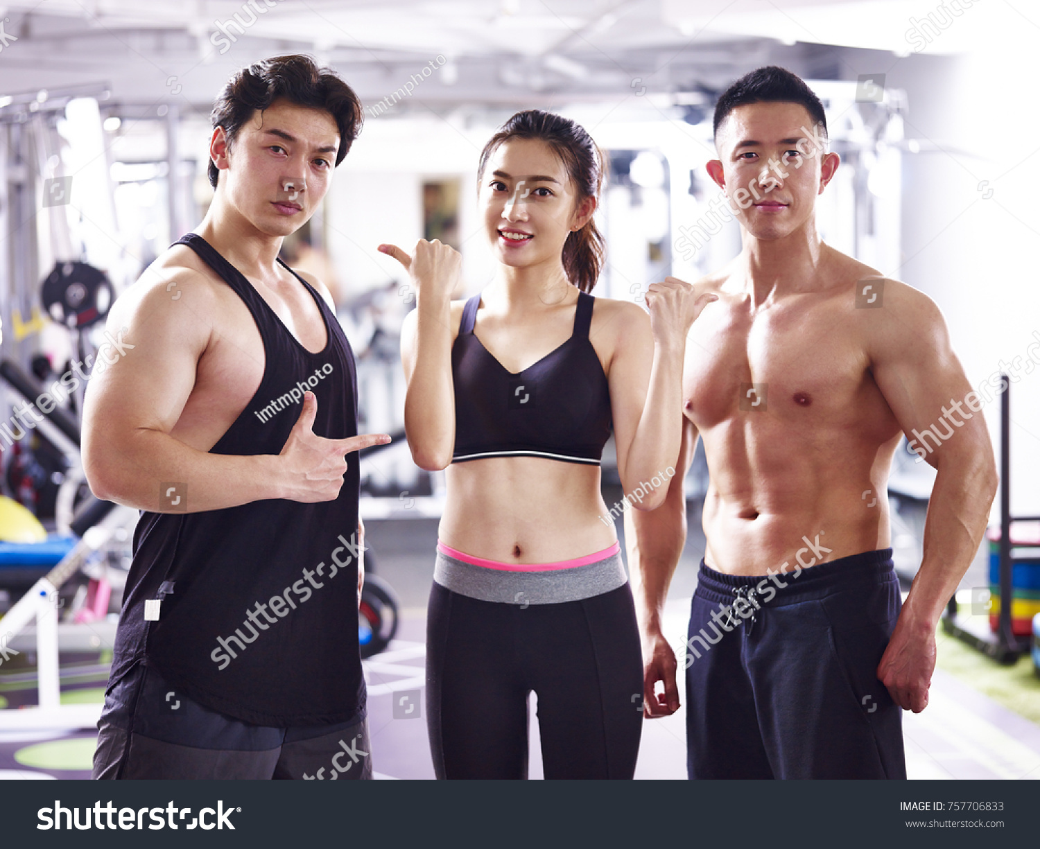 asian bodybuilders  two men and one woman  posing in gym showing muscles.