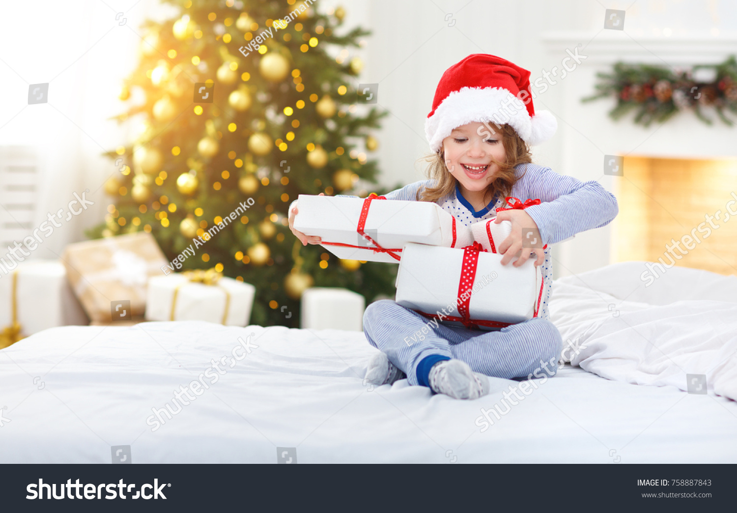 happy funny child girl  with gifts  in bed on Christmas morning