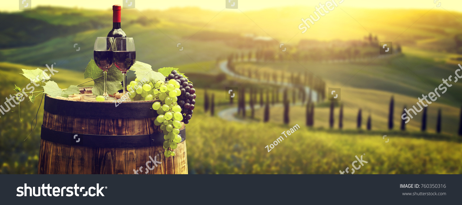 Red wine bottle and wine glass on wodden barrel. Beautiful Tuscany background