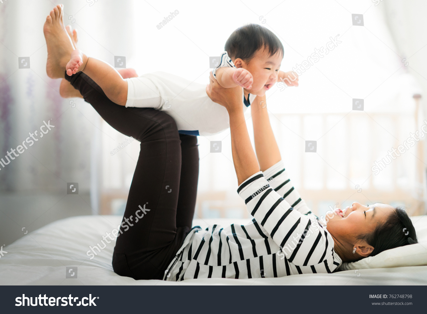 Asian mother play with her baby on the bed   mother  kid  home  baby and family concept