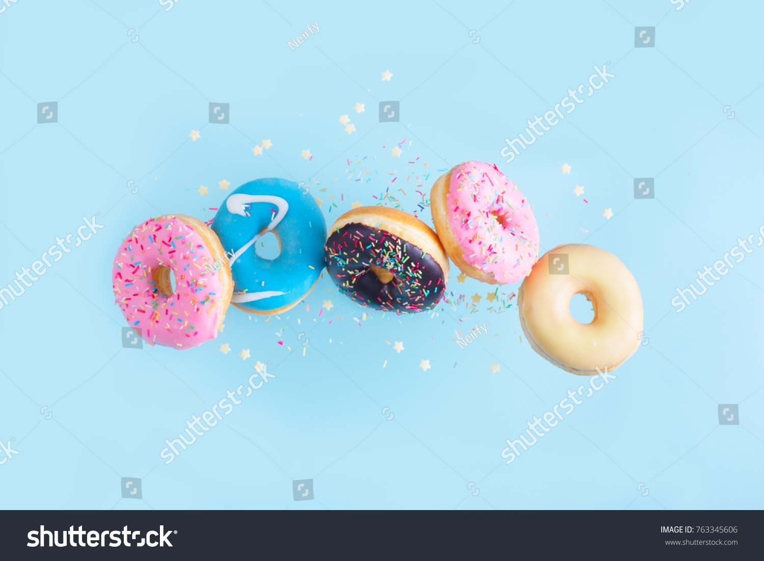 flying doughnuts - mix of multicolored sweet donuts with sprinkles on blue background