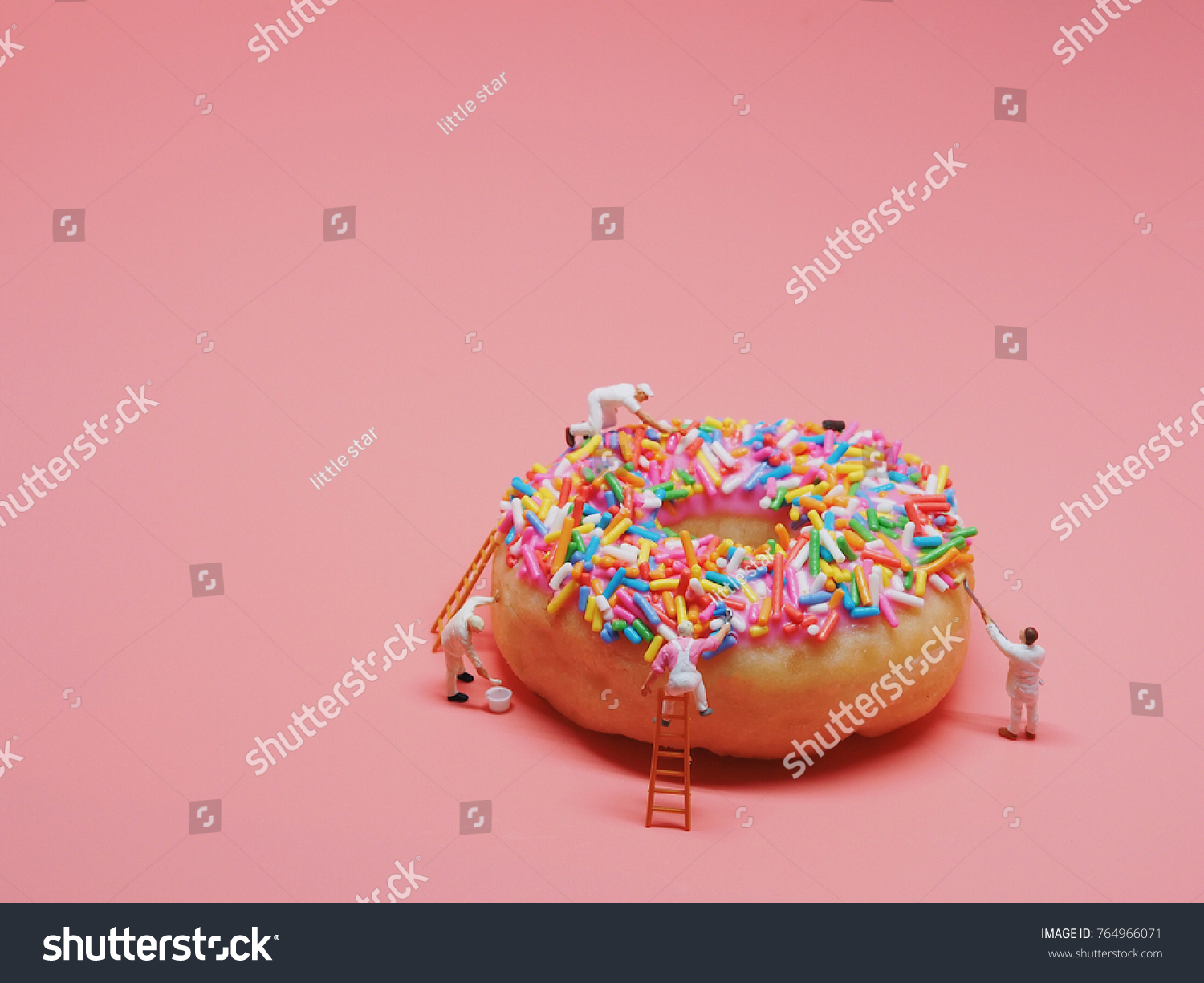 Miniature people painting color on donut.