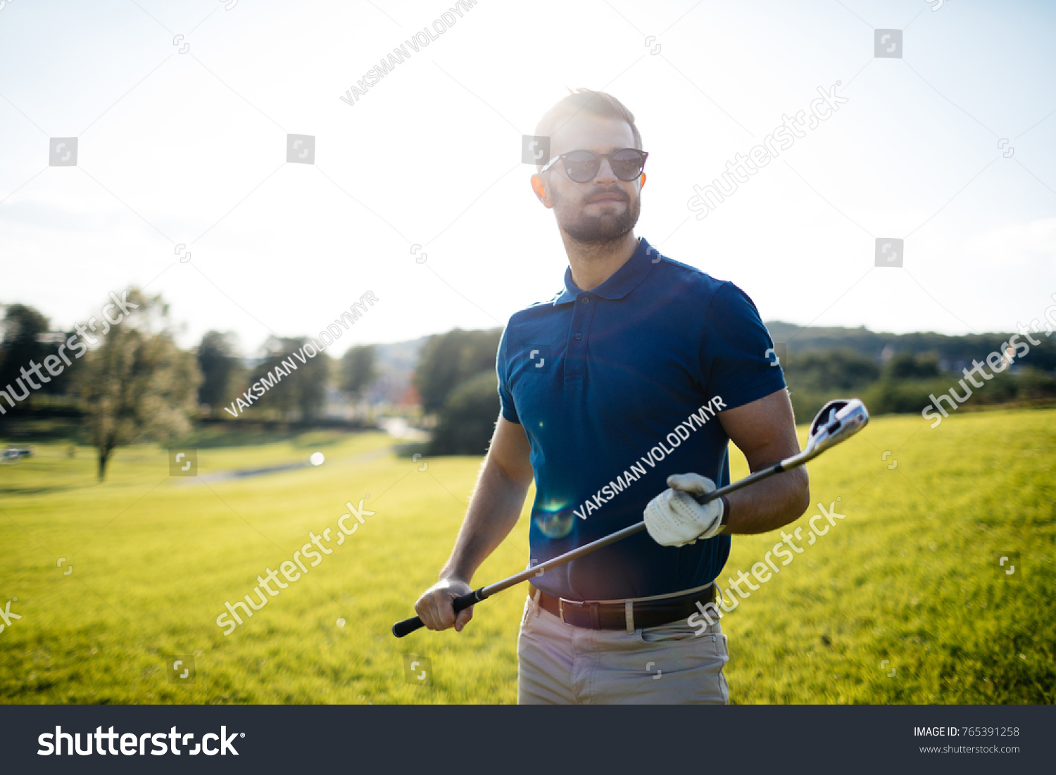 golf player hitting shot with club on course at beautiful morning with sun flare in background