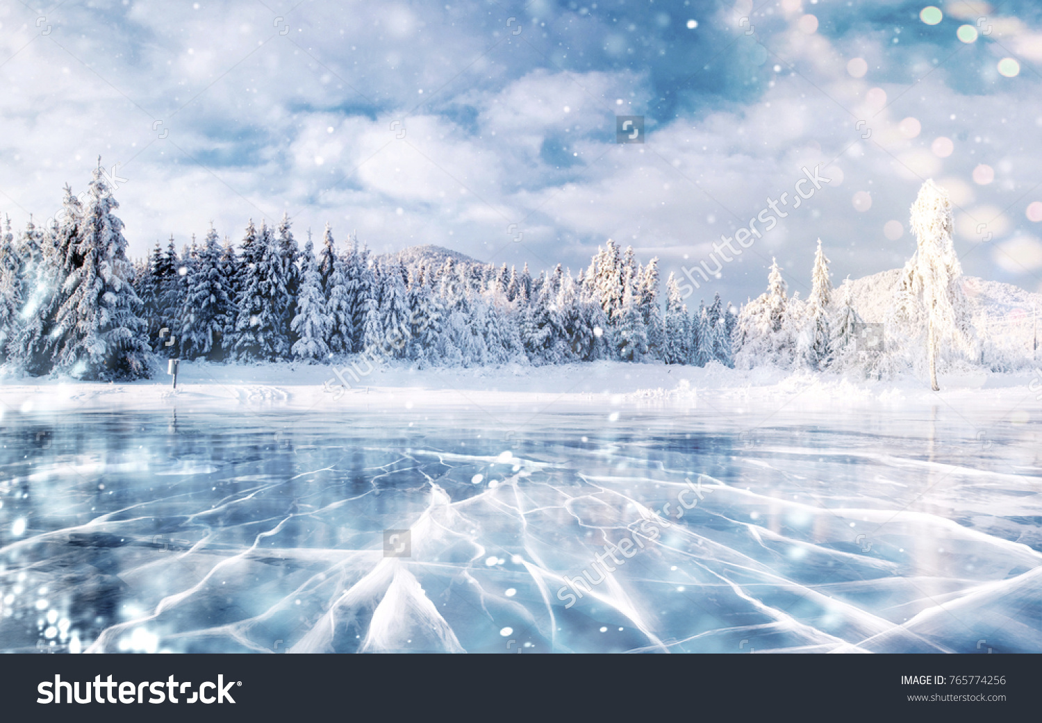 Cracks on the surface of the blue ice. Frozen lake in winter mountains. It is snowing. The hills of pines. Carpathian Ukraine Europe