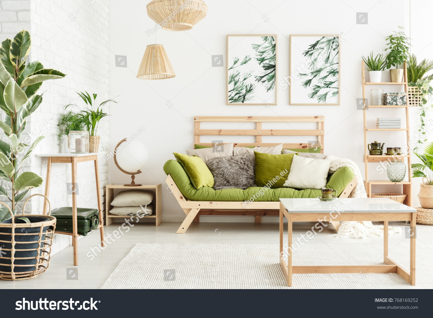 Globe shaped lamp placed on wooden table standing next to green couch in stylish living room interior