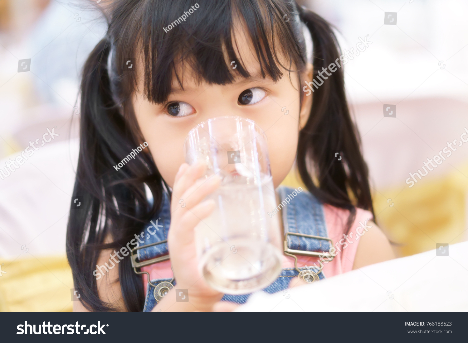 asian children cute or kid girl thirsty and drinking cold water with ice in glass for healthy