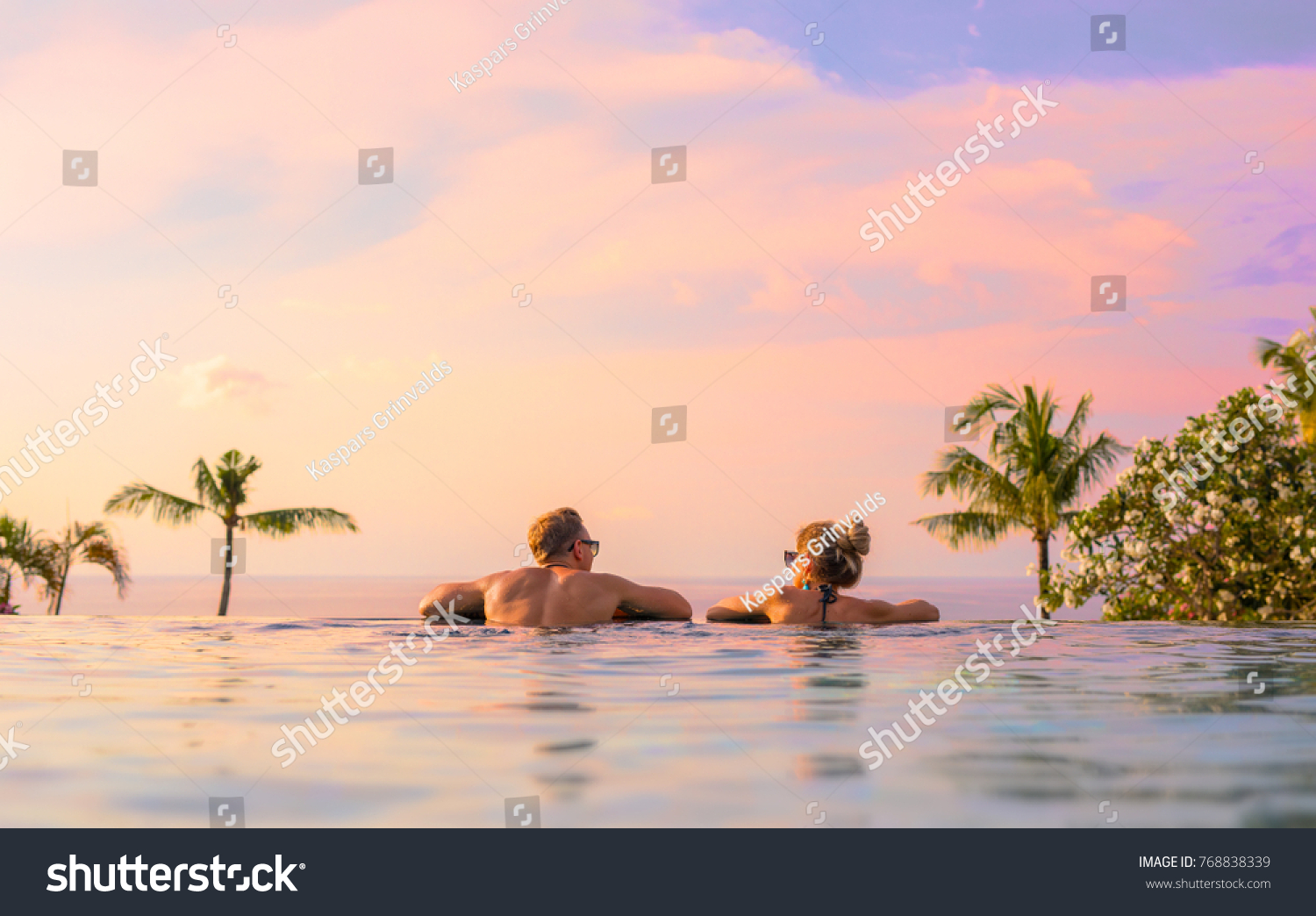 Romantic couple looking at beautiful sunset in luxury infinity pool