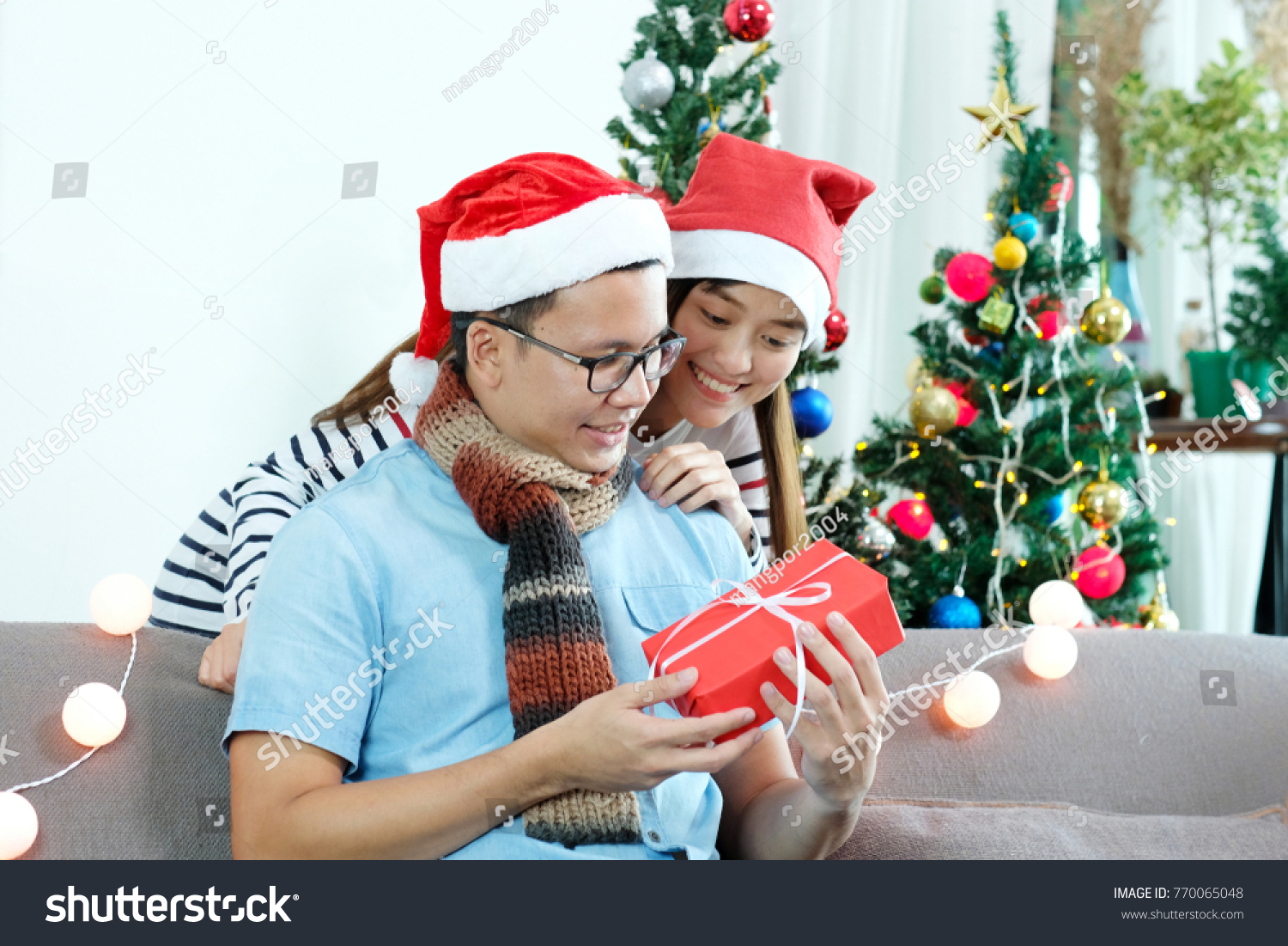 Young asian couple giving red Christmas gift box at Christmas celebate party at home Christmas couple concept