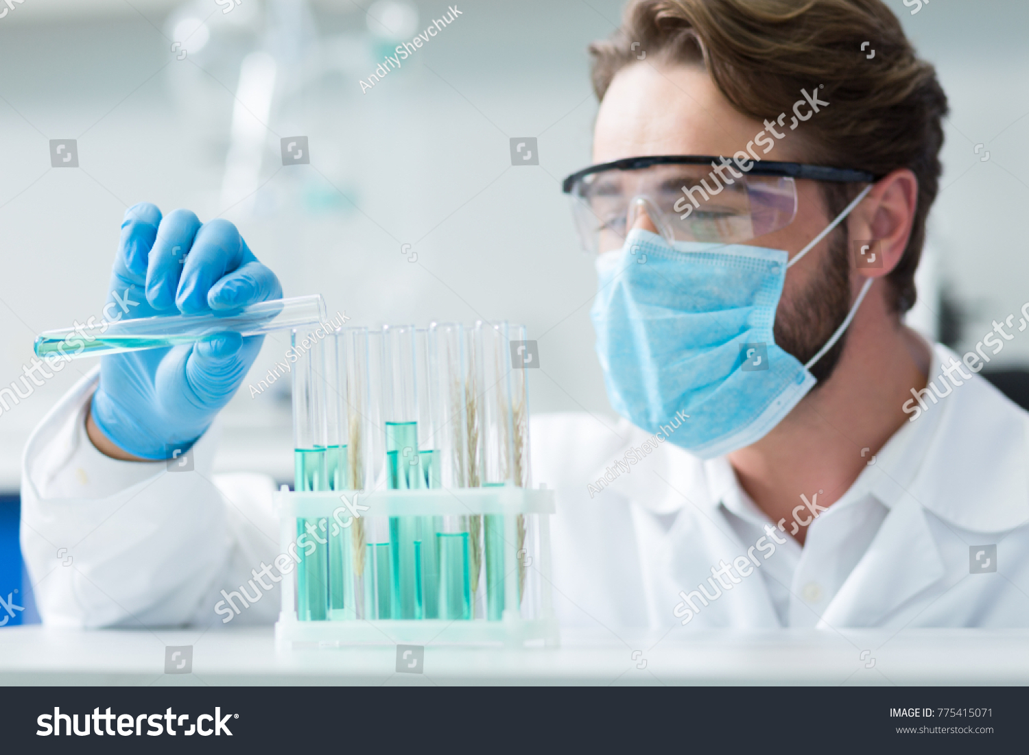 Organic chemistry. Selective focus of test tubes standing on the shells while being looked at by nice smart male chemist