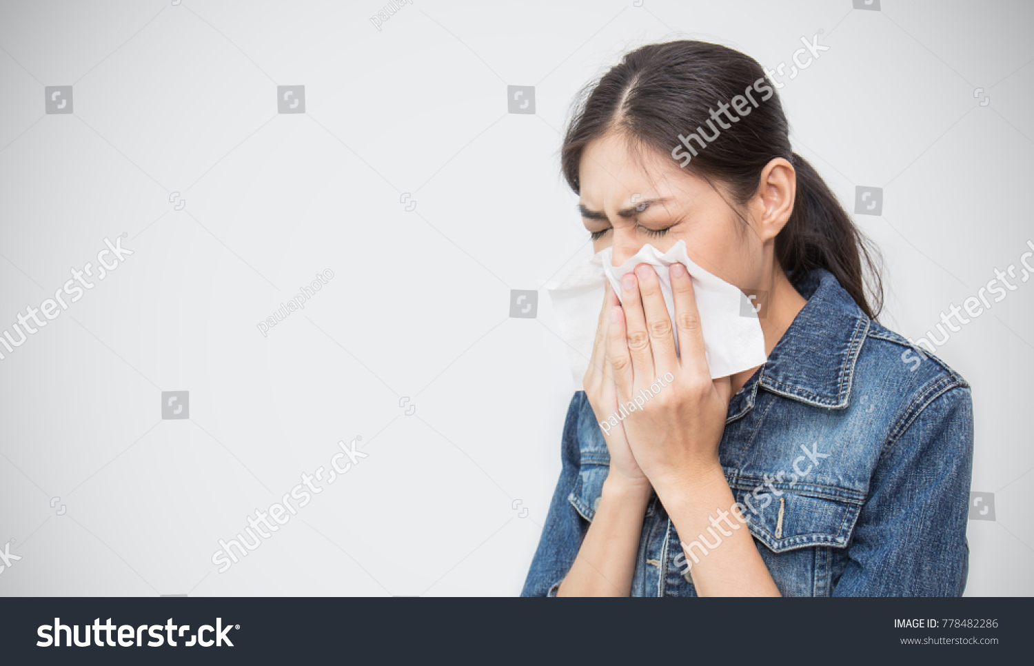 Woman with a cold blowing her runny nose with tissue. Portrait of Asian beautiful girl get sick sneezing from flu. Healthcare and medical concept.