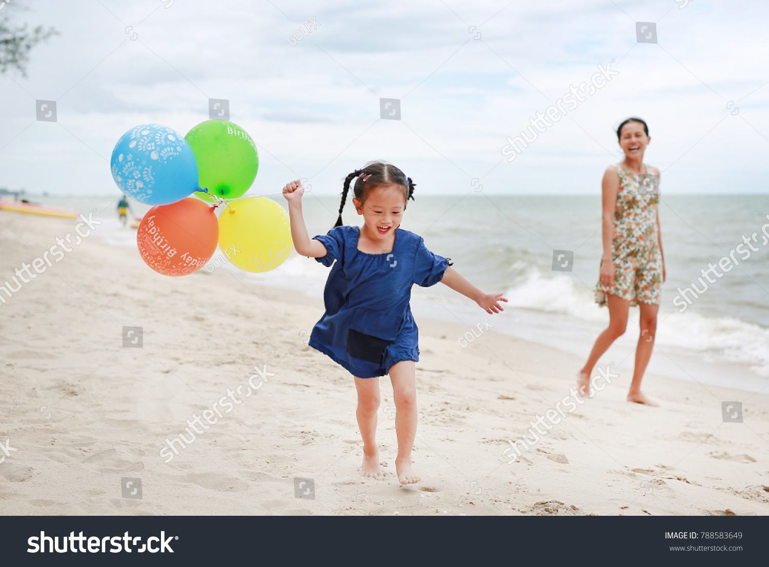 Happy mother and daughter playing balloon on beach. Holiday concept.