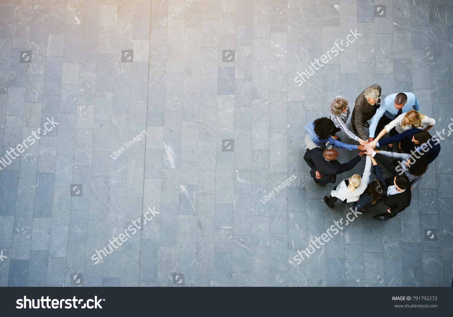 High angle view of a team of united businesspeople standing with their hands together in a huddle in the lobby of a modern office building