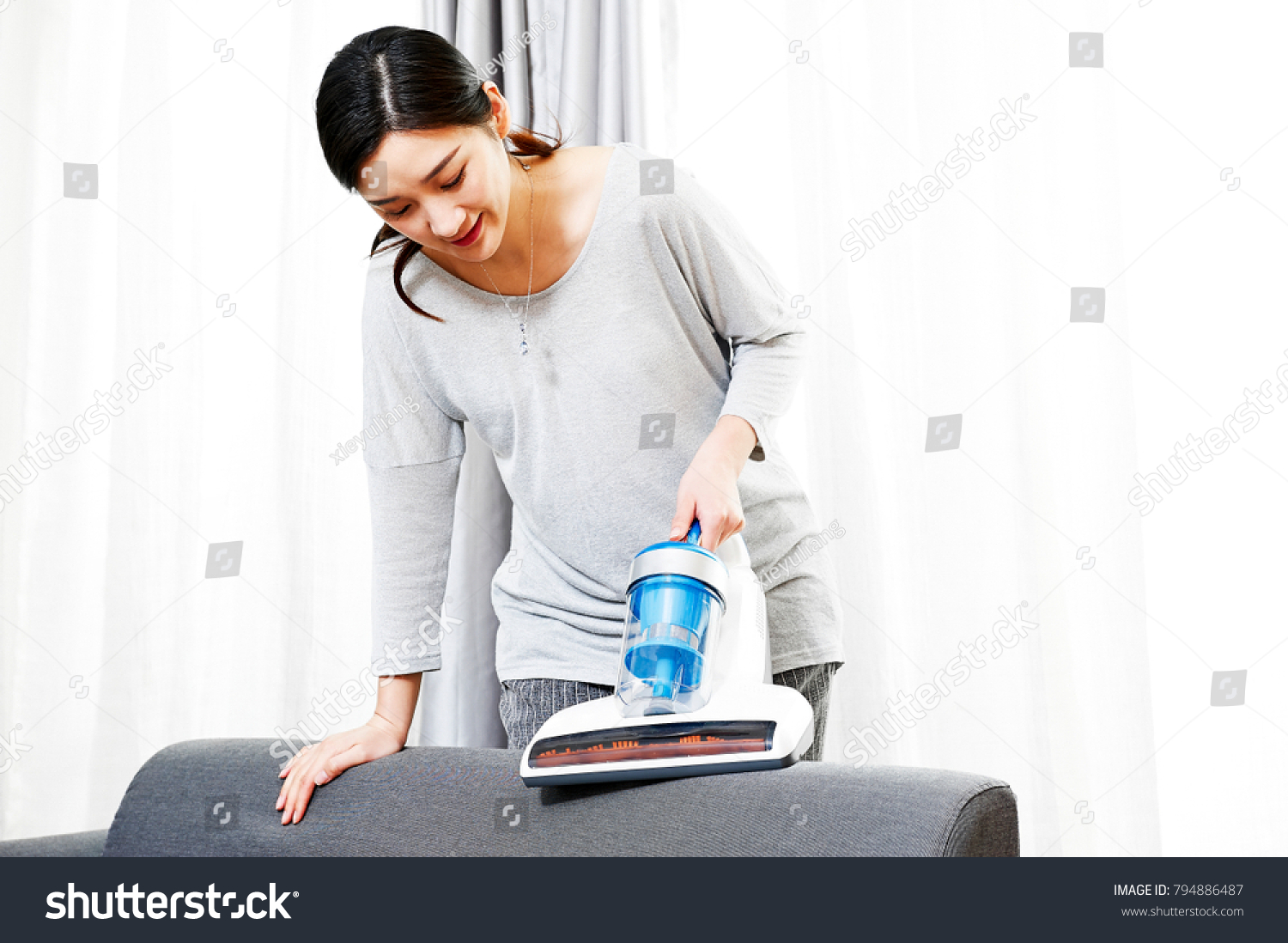 Young Asian women who do housework clean the mites in the couch using a vacuum cleaner