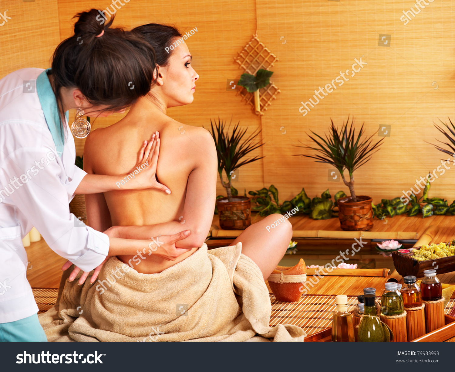 Young woman getting massage in bamboo spa..