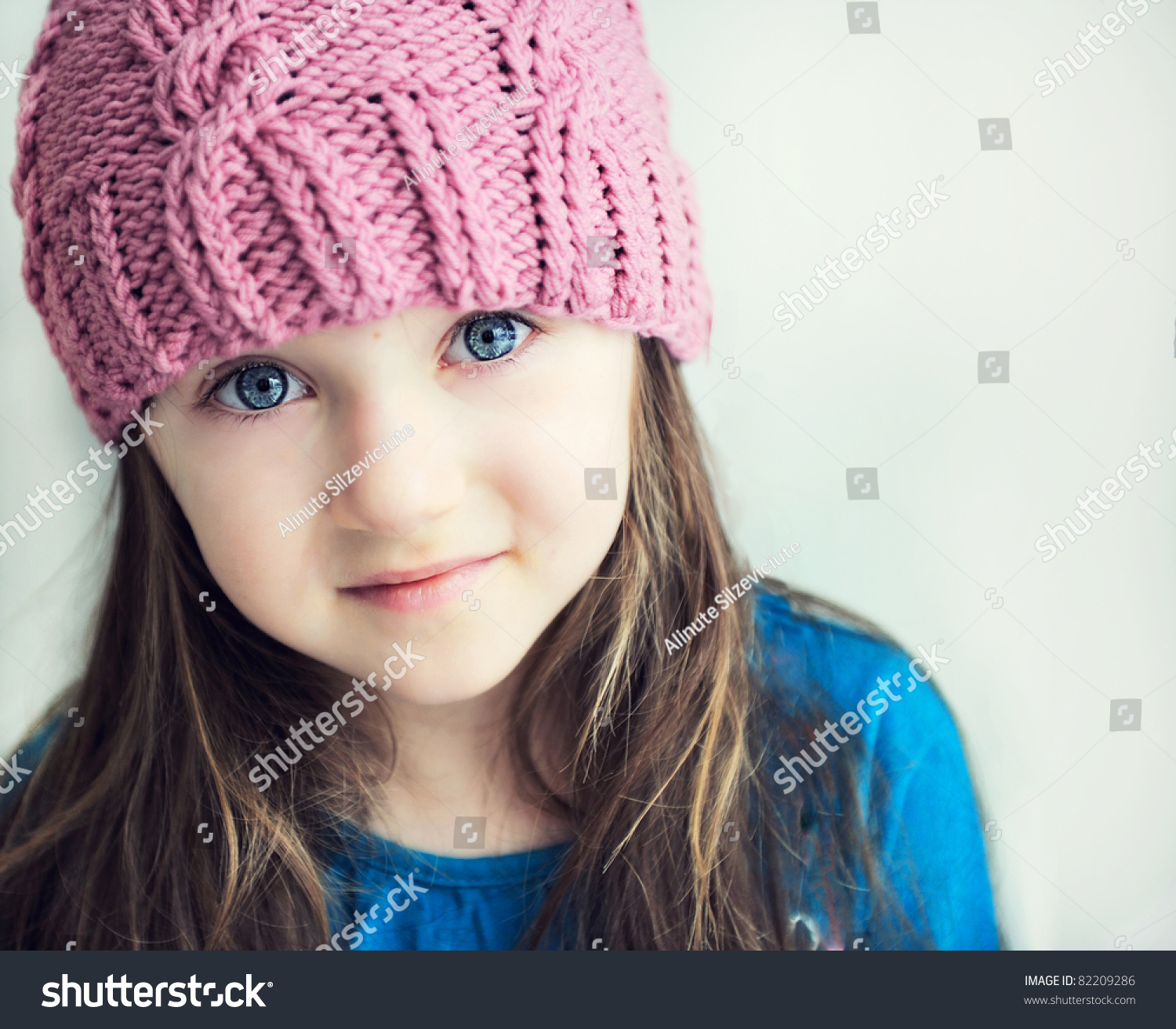 Close-up portrait of adorable smiling child girl wearing pink knitted hat