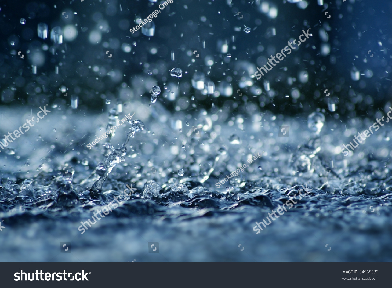 View of falling rain cast in a blue light.