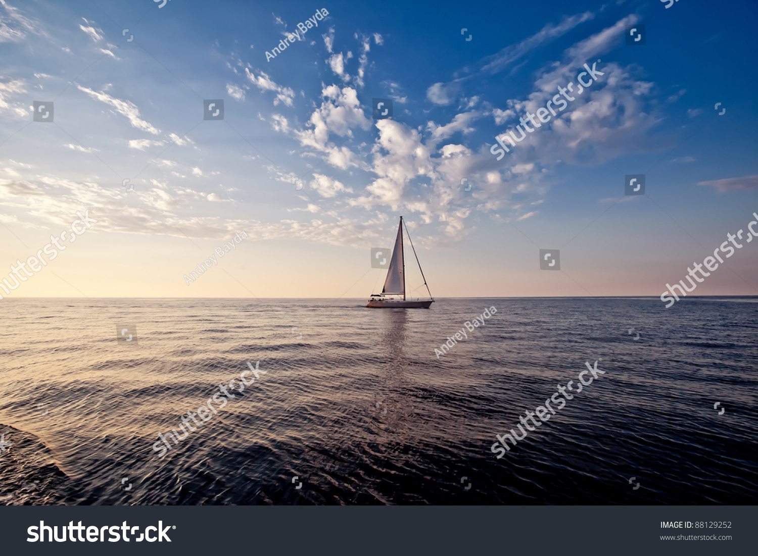 Lonely yacht with white sail in open sea at sunset