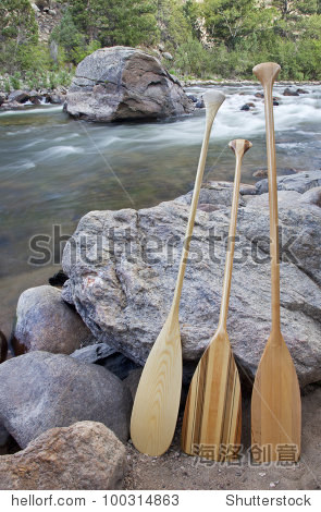 three wooden canoe paddles on shore of mountain river - cache la