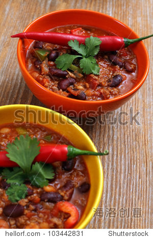 photo of two bowls of chili resting on an old wood table.
